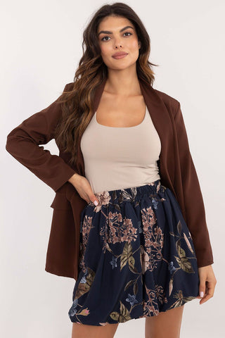 Woman wearing floral patterned mini skirt in bomber style paired with beige top and brown blazer