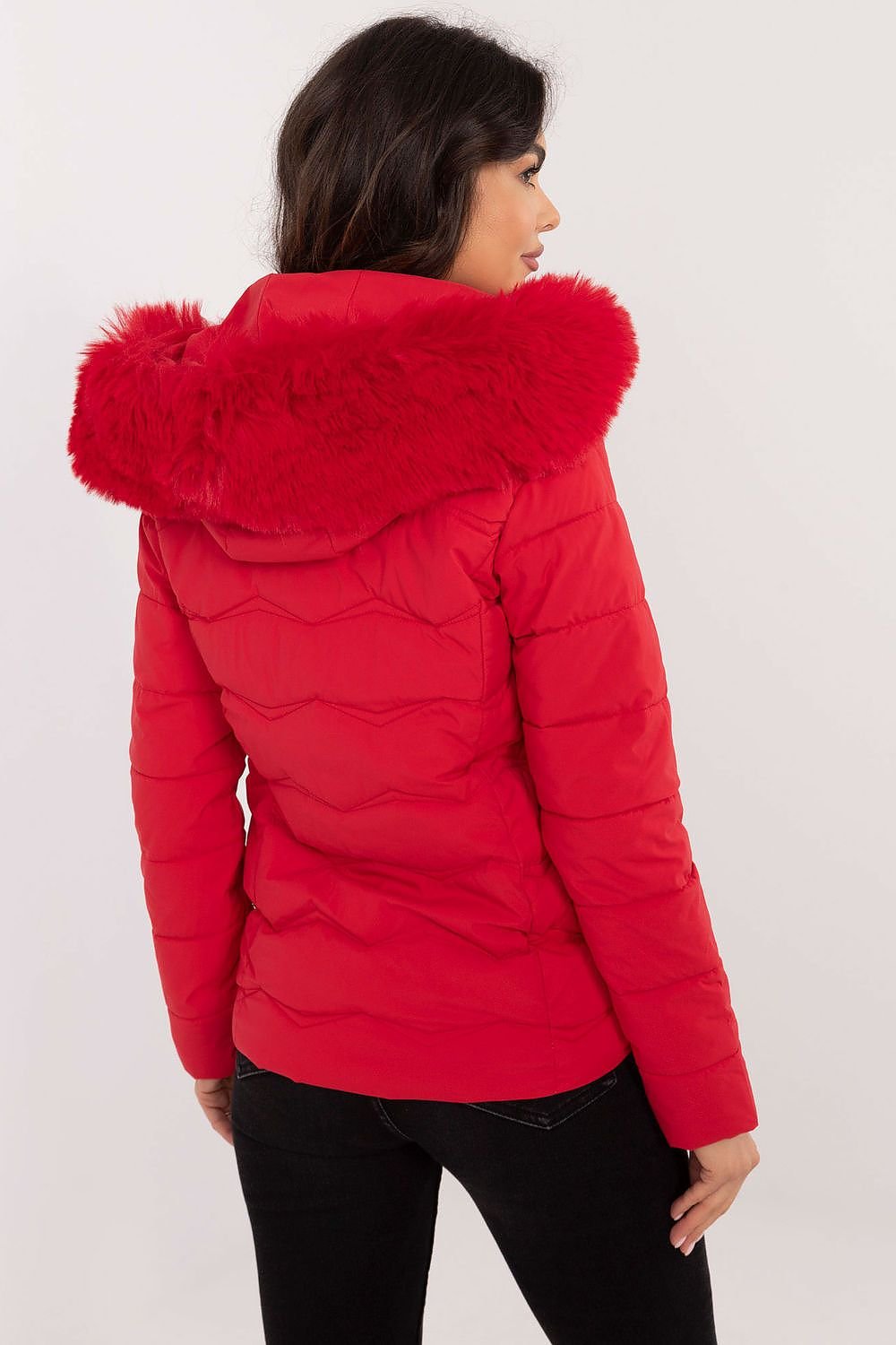 Woman wearing a stylish red women’s winter jacket with quilted design and faux fur hood.