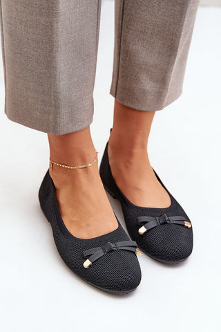Women's black mesh ballet flats with a bow, eco-leather insole, styled with grey trousers.