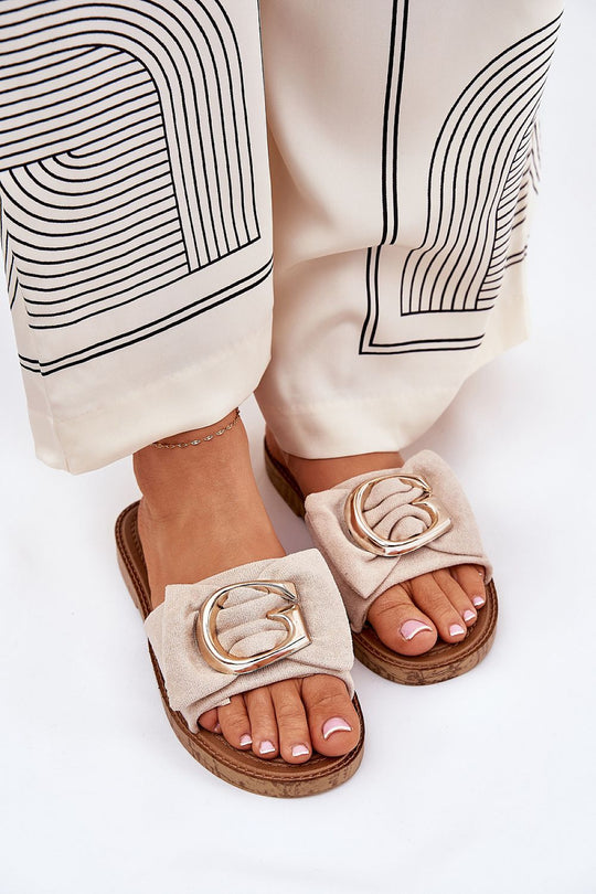Beige flip-flops with faux suede, gold detail, worn with patterned pants.