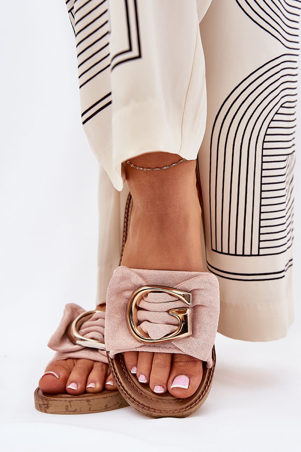 Beige flip-flops with faux suede and gold detail, enhancing summer outfits with elegance.